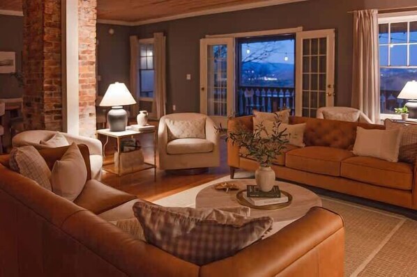 A cozy living room with a brown leather sofa, a beige armchair, and a coffee table with a vase.