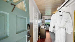 A hallway with a door marked '7', a kitchen area with a refrigerator and microwave, and a white robe hanging on the wall. - Historic Riverview Inn - King Room Seven (Chattanooga)