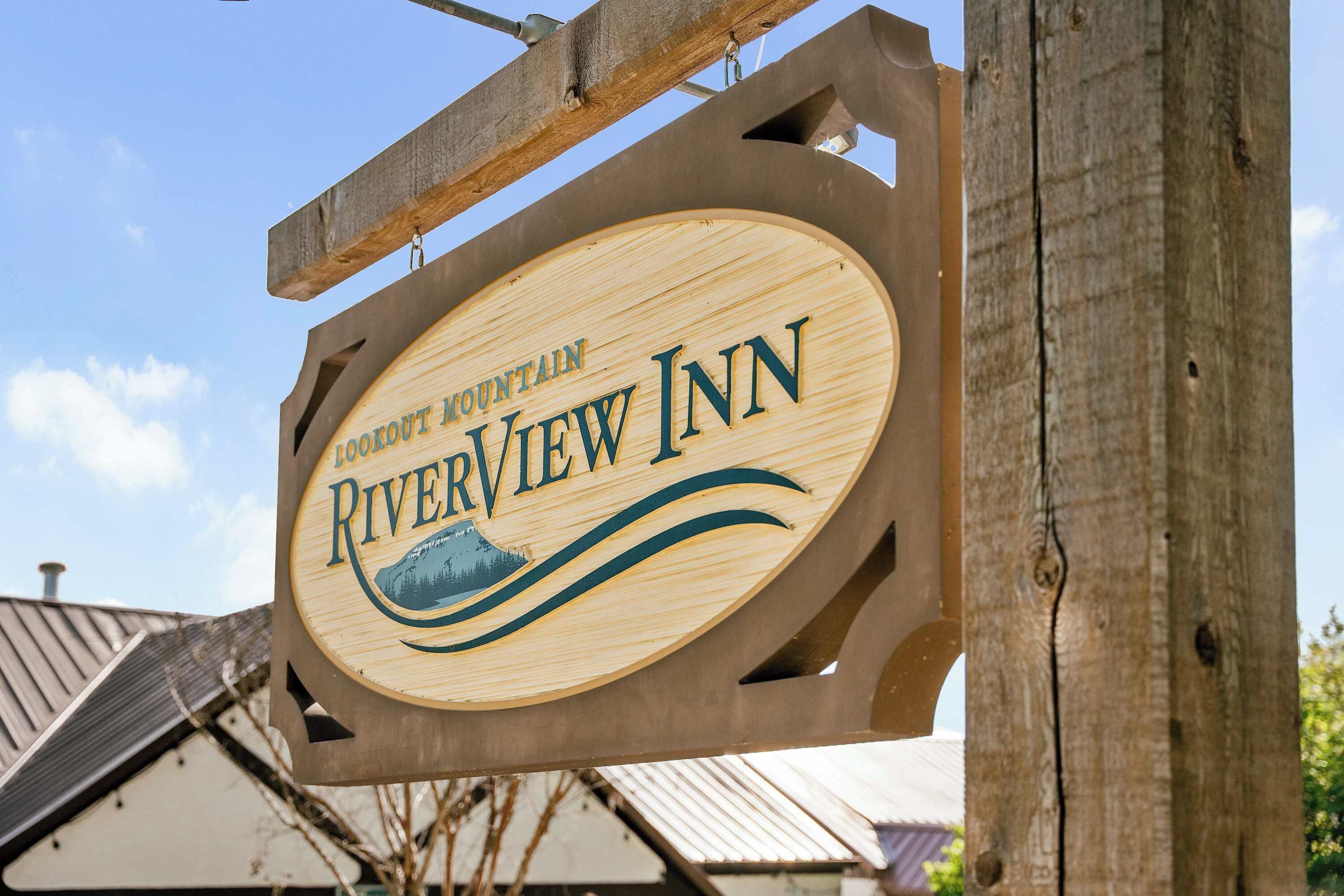 Une enseigne en bois pour le Riverview Inn, ornée d’un motif représentant une montagne.