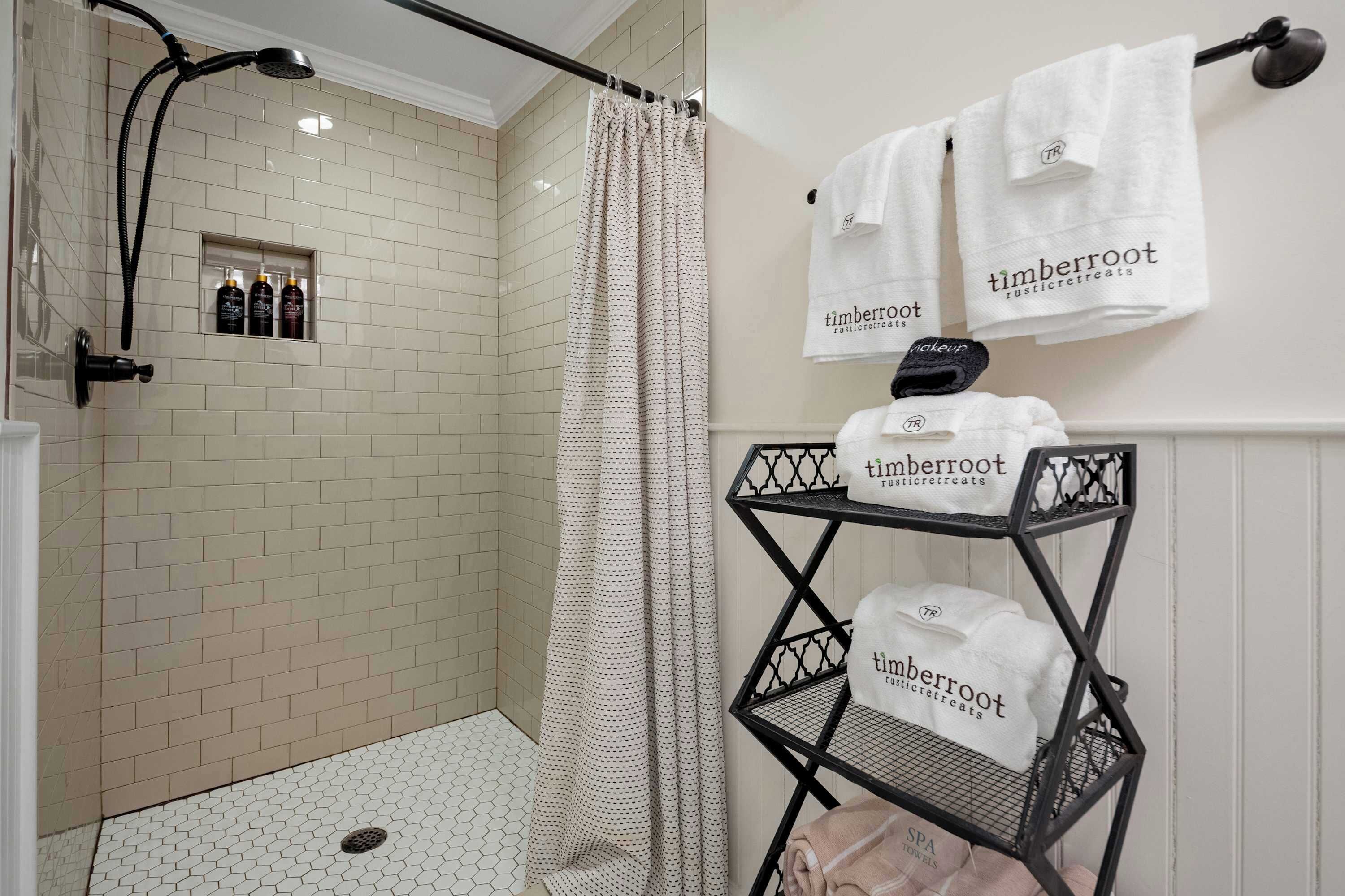 A shower with a handheld showerhead, a shower curtain, and a shelf with towels.