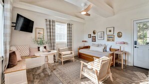 A bedroom with a bed, a desk, a chair, a sofa, a TV, and a door. - Lookout Mountain Cottage (Lookout Mountain)