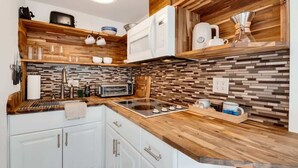 A kitchen with wooden shelves, a microwave, a toaster, and a tiled backsplash. - Lookout Mountain Cottage (Lookout Mountain)