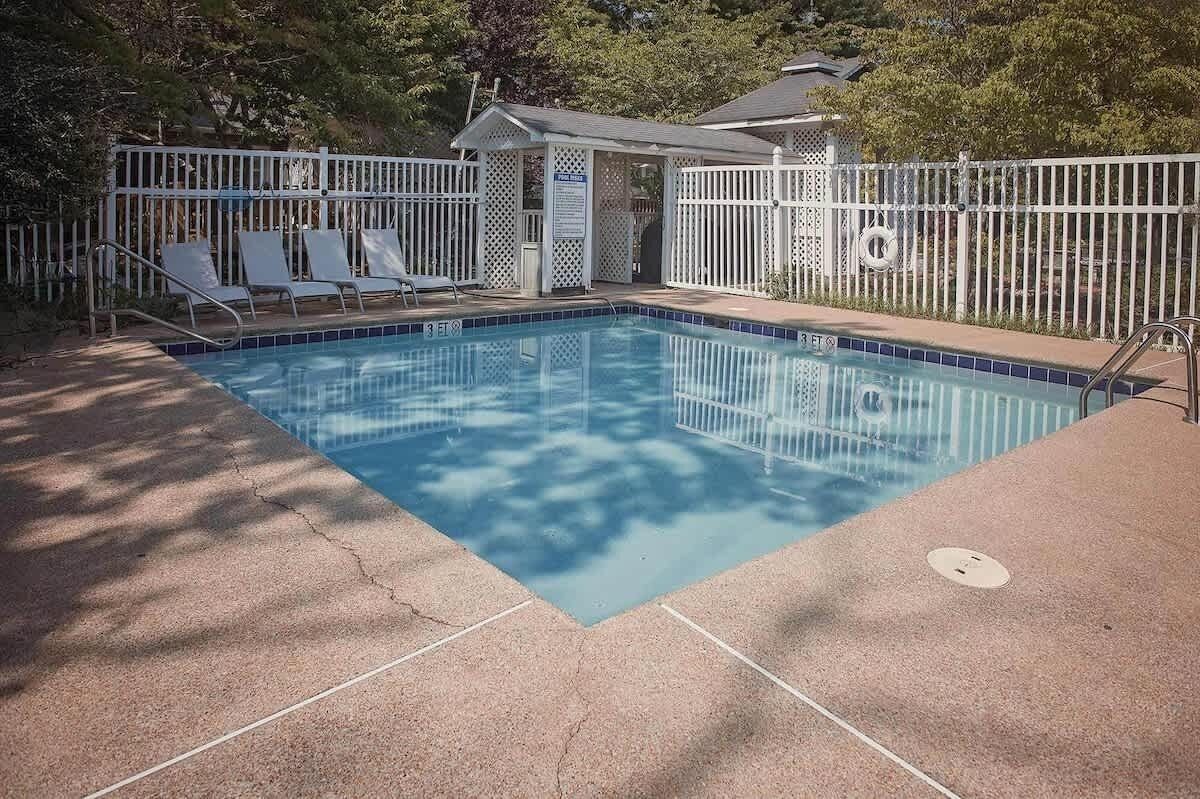 Une piscine dotée d’une terrasse entourée d’une clôture, de chaises longues et d’un espace abrité.