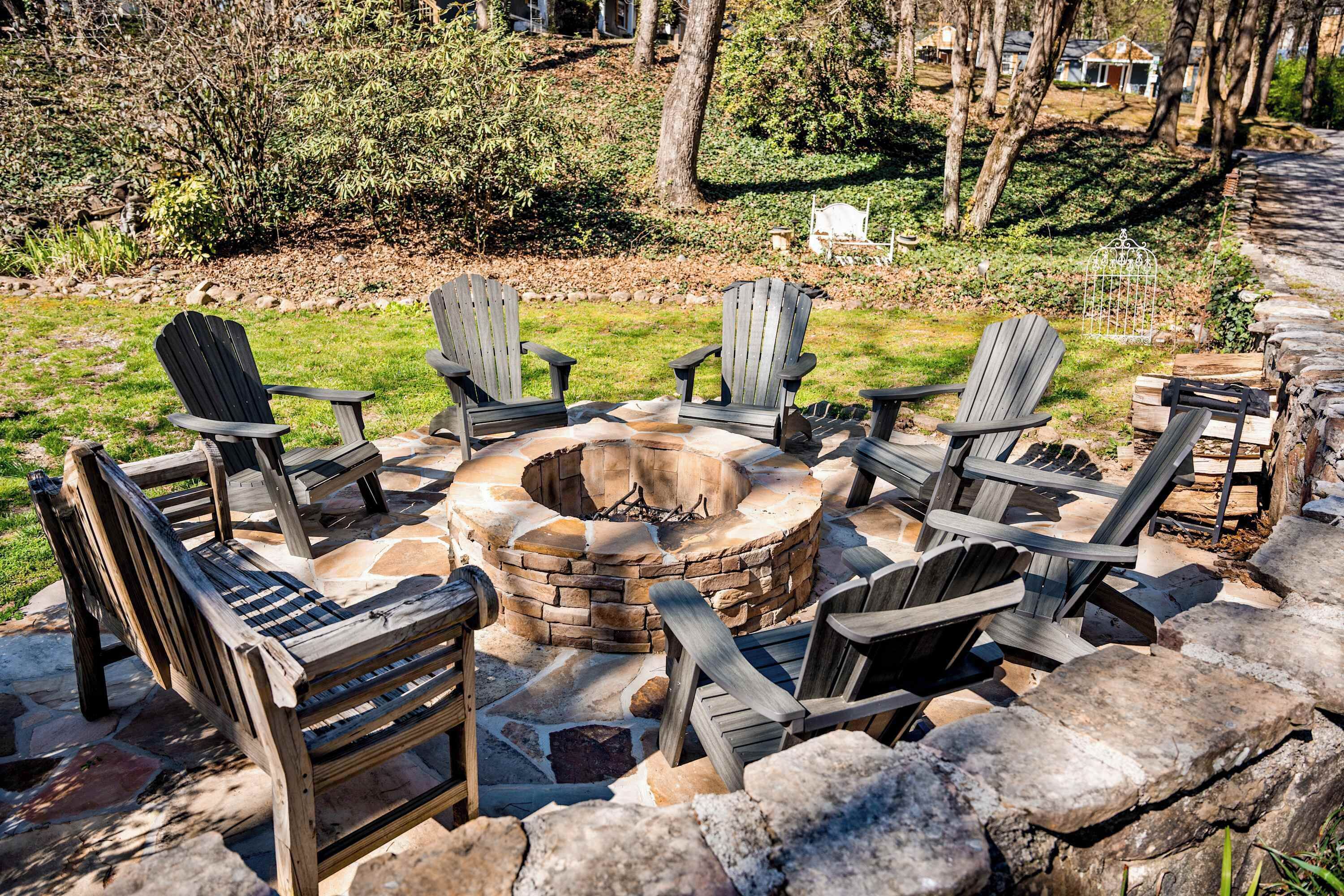 Een vuurkorf van steen omringd door Adirondack stoelen in een aangelegd buitengebied.