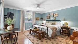 Une chambre à coucher avec un lit, une table de chevet, une commode et une fenêtre avec des rideaux.