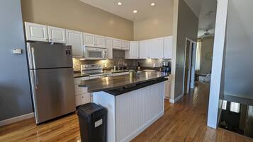 Enjoy cooking in this well-equipped kitchen with a central island, white cabinetry, and stainless steel appliances.