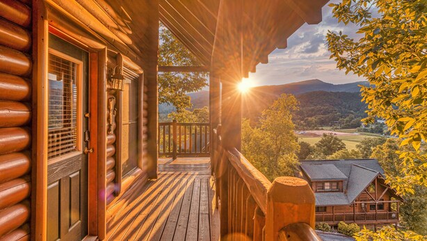 A wooden cabin with a porch, a window with a metal grill, and a view of a valley with trees and hills. - Smoky Mountain Summer Fun Near Dolly! Pool + Arcade + Gaming Wall! (Sevierville)