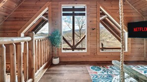 A wooden cabin with a balcony, a potted plant, and a Netflix sign. - Smoky Mountain Summer Fun Near Dolly! Pool + Arcade + Gaming Wall! (Sevierville)