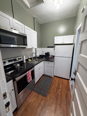 A compact kitchen with a microwave, stove, sink, and refrigerator.