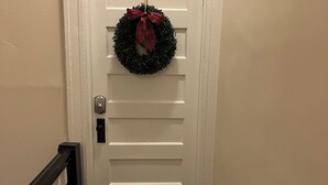 A white door with a wreath and a doormat.