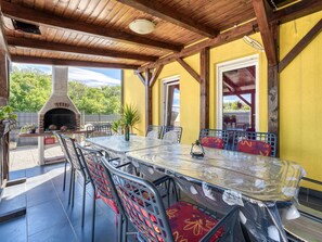 An outdoor patio with a brick oven, metal chairs, and a glass table. - Radmila 1 by Interhome (Krk/Šilo)