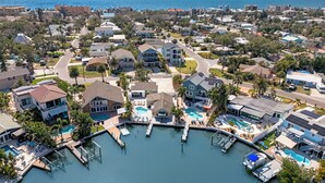 Vista aérea de una zona residencial costera con un puerto deportivo, casas y una piscina grande.