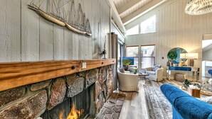 Un salón acogedor con chimenea de piedra, un sofá azul y un ventanal grande.