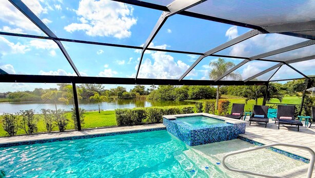 A swimming pool with clear blue water, a hot tub, and lounge chairs. - Tropical Oasis, Heated Pool & Spa, Bikes - Villa 7 Palms - Roelens (Cape Coral)