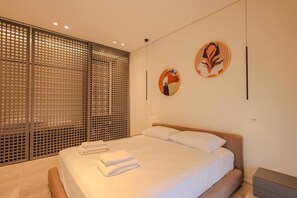 Ein modernes Schlafzimmer mit einem großen Bett, einer Holztür mit Schieberiegel und zwei runden Wandbildern.