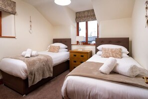 A bedroom with two beds, a nightstand, and a window with a view. - Thomas Fold Cottage - Ambleside (Ambleside)