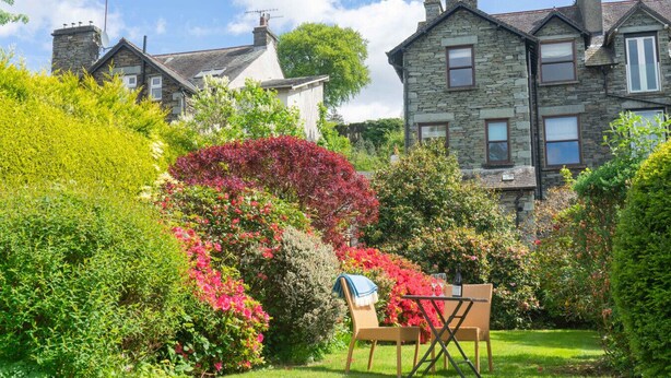 Una casa in pietra con giardino, una sedia e un tavolo.
