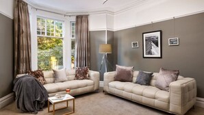 A living room with two beige sofas, a floor lamp, and a coffee table. - The Firs - Centre of Bowness, parking for 5+ cars (Bowness-on-Windermere)