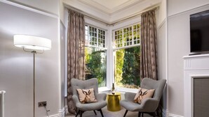 A room with two grey armchairs, a floor lamp, a fireplace, and a bay window with curtains. - The Firs - Centre of Bowness, parking for 5+ cars (Bowness-on-Windermere)
