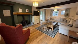 A cozy living room with a fireplace, a sofa, a red armchair, and a coffee table.