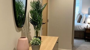 A hallway with a wooden dresser, a mirror, and two potted plants.