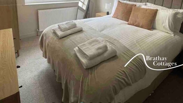 A bedroom with a large bed, a radiator, a window with blinds, and a ceiling light fixture.