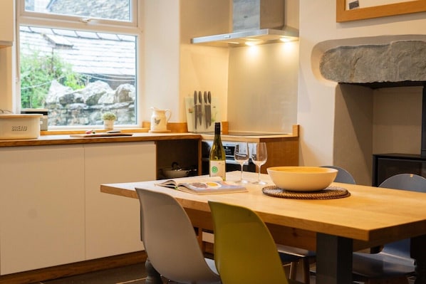 A compact kitchen with a window, a dining table, chairs, and a stone accent wall.