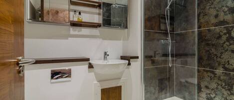A modern bathroom with a white sink, mirror, and toilet.