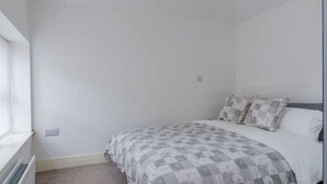 A bedroom with a bed, a window, and a radiator.