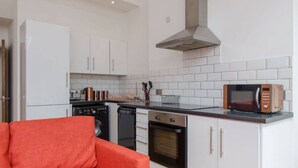 A compact kitchen with white cabinets, a microwave, a stove, and a dishwasher.
