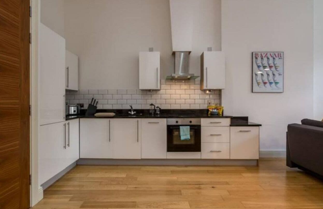 A modern kitchen with white cabinets, a black countertop, and a tiled backsplash.