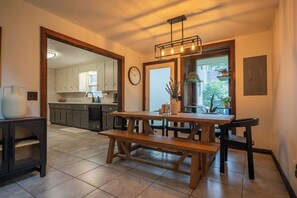 Een moderne keuken met houten kasten, een eettafel met banken en een inbouwoven.