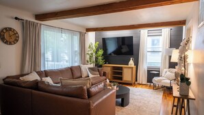 Een moderne woonkamer met een bruine leren bank, een flatscreen televisie en een houten tv-meubel.