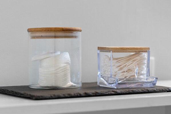 Deux bocaux en verre, dotés de couvercles en bois, sont posés sur une surface sombre.