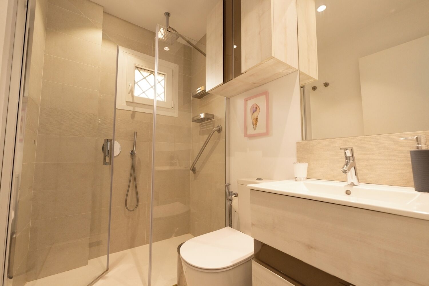 A modern bathroom with a glass-enclosed shower, a toilet, and a sink with a mirror above.