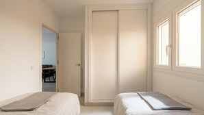 Ein Schlafzimmer mit zwei Betten, einem Kleiderschrank und einem Fenster.