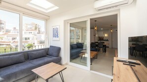 Ein modernes Apartment mit einem grauen Sofa, einem Holztisch und einem Essbereich mit einer Küche im Hintergrund.