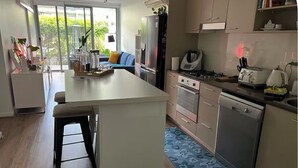 A modern kitchen with a central island, stainless steel appliances, and a blue patterned rug.