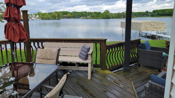 A wooden deck with outdoor furniture, a covered area, and a view of a lake.