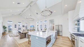 A spacious kitchen with a large island, stainless steel appliances, and a modern chandelier. - Elegant Beach House with views, resort pool, golf, restaurants - steps to beach (Port Aransas)