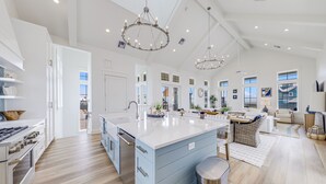 A spacious kitchen with a large island, modern appliances, and pendant lighting. - Elegant Beach House with views, resort pool, golf, restaurants - steps to beach (Port Aransas)