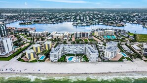 Un paisaje urbano costero con un puerto deportivo, edificios residenciales y una playa.