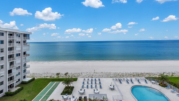 Un hotel con piscina, sillas de descanso y vistas a la playa y al océano.