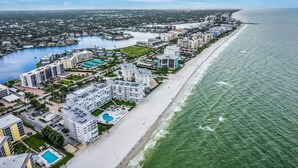 Un complejo turístico frente al mar con hoteles en la playa, un puerto deportivo y una amplia zona de piscina.