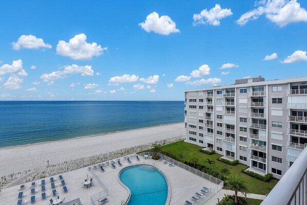 Un hotel con piscina, vistas a la playa y varios balcones.