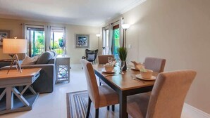 Un salon moderne avec un canapé, une table à manger, des chaises et une lampe.