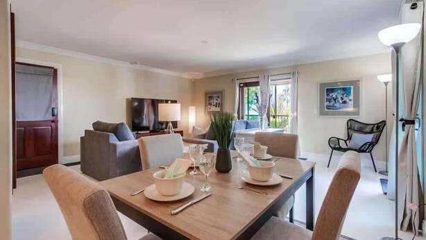 Un coin repas avec une table dressée pour quatre personnes, un canapé, un téléviseur et un fauteuil.