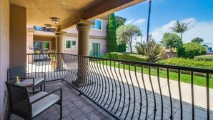 Un balcon doté d’une balustrade métallique incurvée, d’une chaise et d’une table.