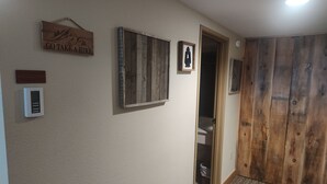 Un couloir avec une porte en bois, un tableau encadré et un thermostat fixé au mur.