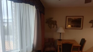 Une pièce comprenant un lit, une table, une chaise, une lampe et un tableau accroché au mur.
